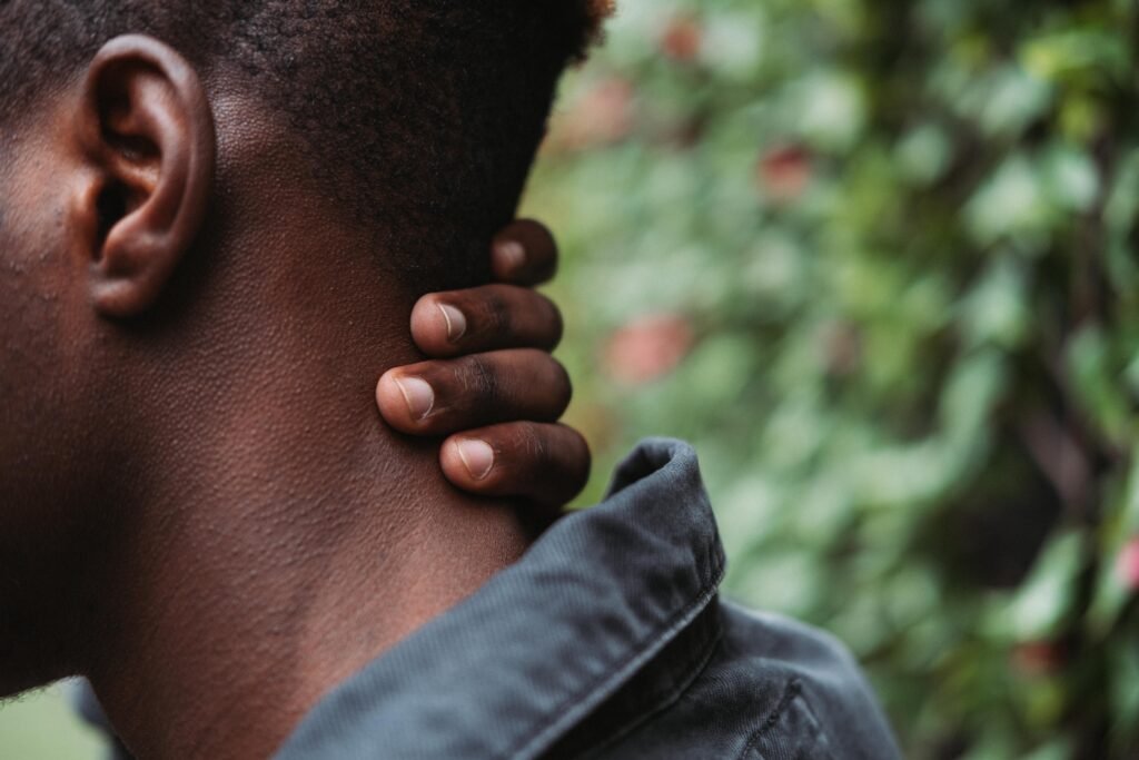 male in denim jacket touching neck